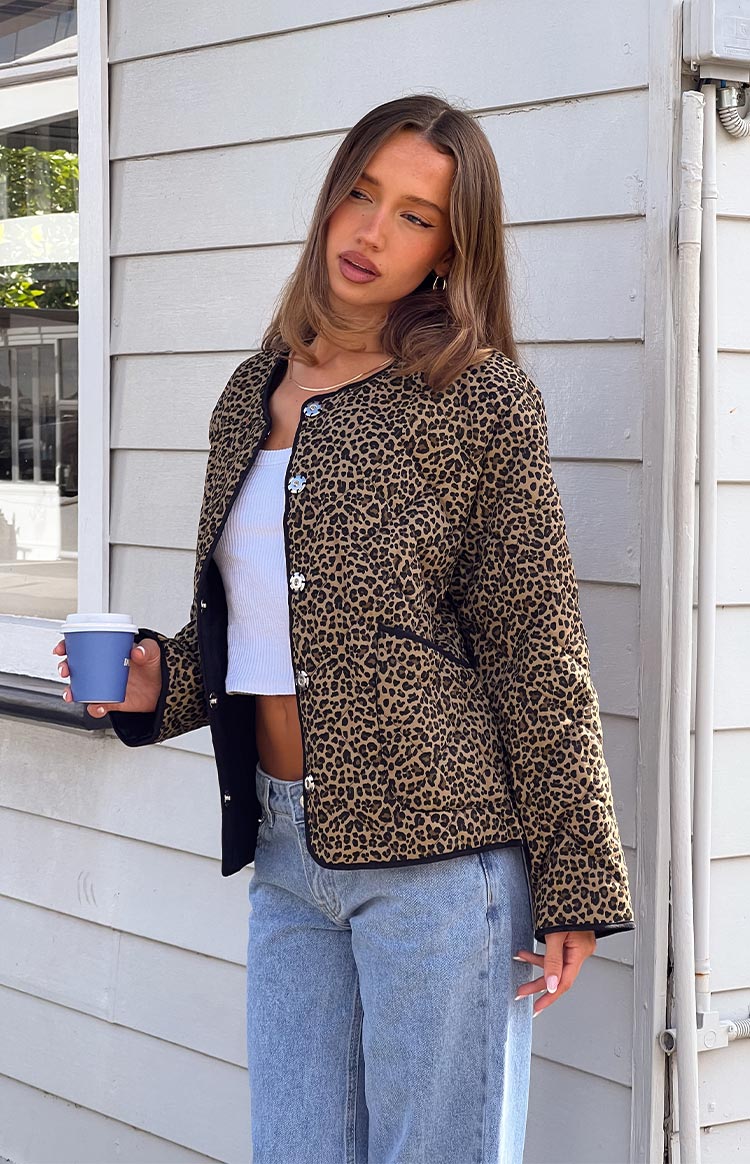 Front view of an open relaxed fit leopard print quilted jacket with black piping, showing decorative silver buttons