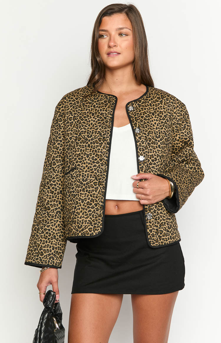Front view of a leopard print quilted jacket with black trim and round silver button closures