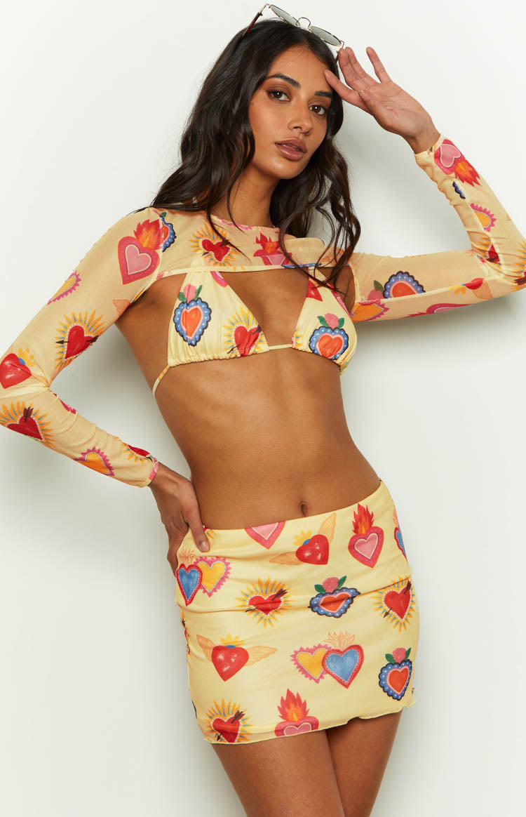 Front view of a fitted yellow mesh mini skirt featuring a colourful all-over heart print
