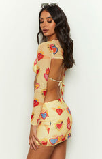 Side view of a yellow mesh mini skirt with a colourful heart print and delicate lettuce hem