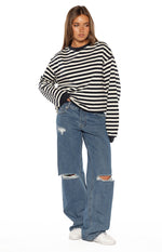 Mid wash blue ripped jeans with a relaxed wide-leg fit and large rips at both knees