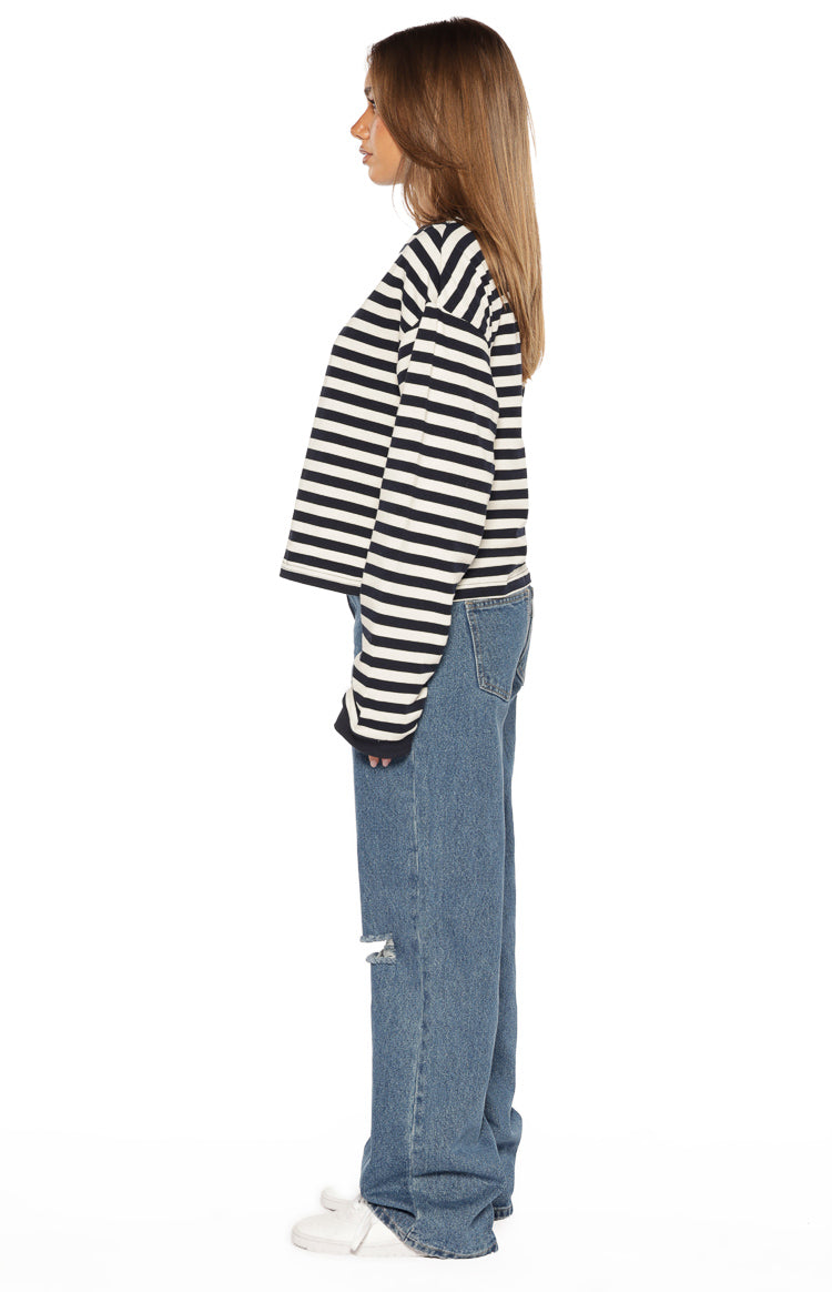 Side view of mid wash ripped jeans with a wide-leg fit and knee rip detail