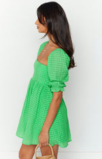 Side view of a green check babydoll mini dress with puff sleeves and a gathered waist