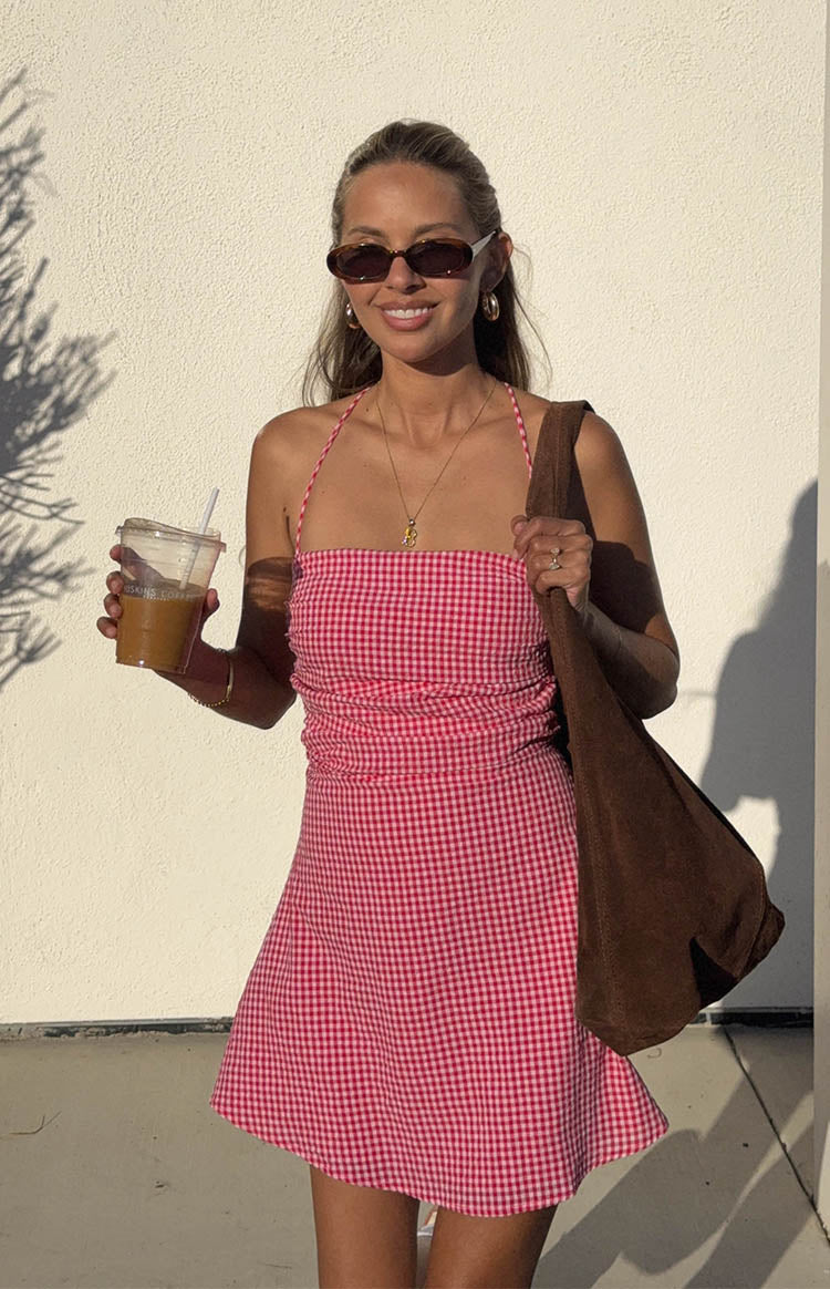 Front view of a red and white gingham mini dress with a ruched bodice and halter neckline