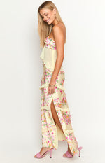 Side view of a yellow floral satin maxi skirt with a high side slit and tiered ruffles