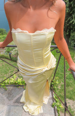 Close-up of a yellow satin strapless maxi dress with a lace-trimmed neckline, corset-style bodice, and ruched twist waist