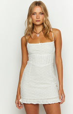 White broderie mini dress with a square neckline, small bow, thin straps, and a ruched corset-style bodice