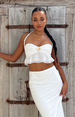 Close-up of the white chiffon halter crop top with a gold shell detail and ruffled peplum hem