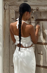 Rear view of a white chiffon crop top with a halter neck tie, exposed zipper, and ruffled hem