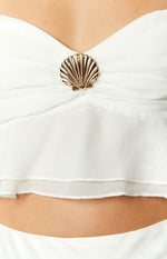 Gold shell detail on the center bust of a white chiffon crop top with layered raw-edge hem