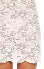 Close-up of the white floral lace pattern and scalloped hemline of the mini dress