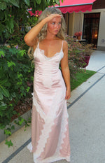Pink satin maxi dress with a V-neckline, spaghetti straps, and diagonal white lace trim panels