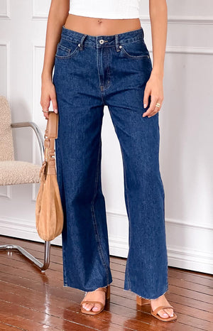 girl wearing dark wash low rise jeans with raw hem details 