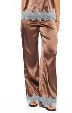 Side view of brown satin wide-leg pants with light blue scalloped lace trim on the hem and side