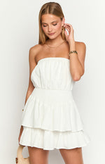Front view of a white strapless mini dress with a shirred waist and tiered ruffle skirt