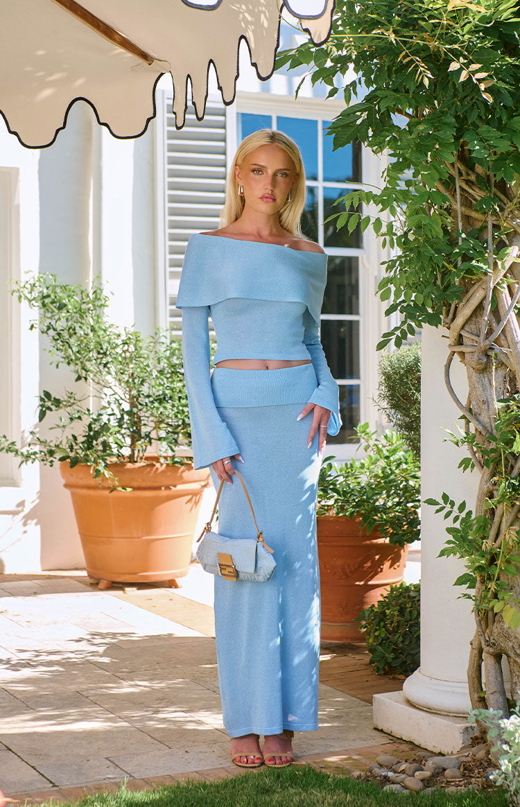 Front view of a cropped blue knit off-shoulder top with wide neckline and flared cuffs