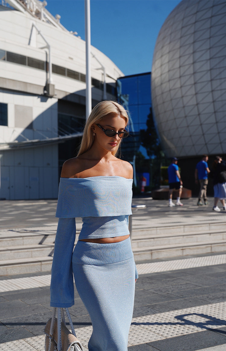 Side view of a light blue knit maxi skirt with a fitted silhouette and ribbed waist