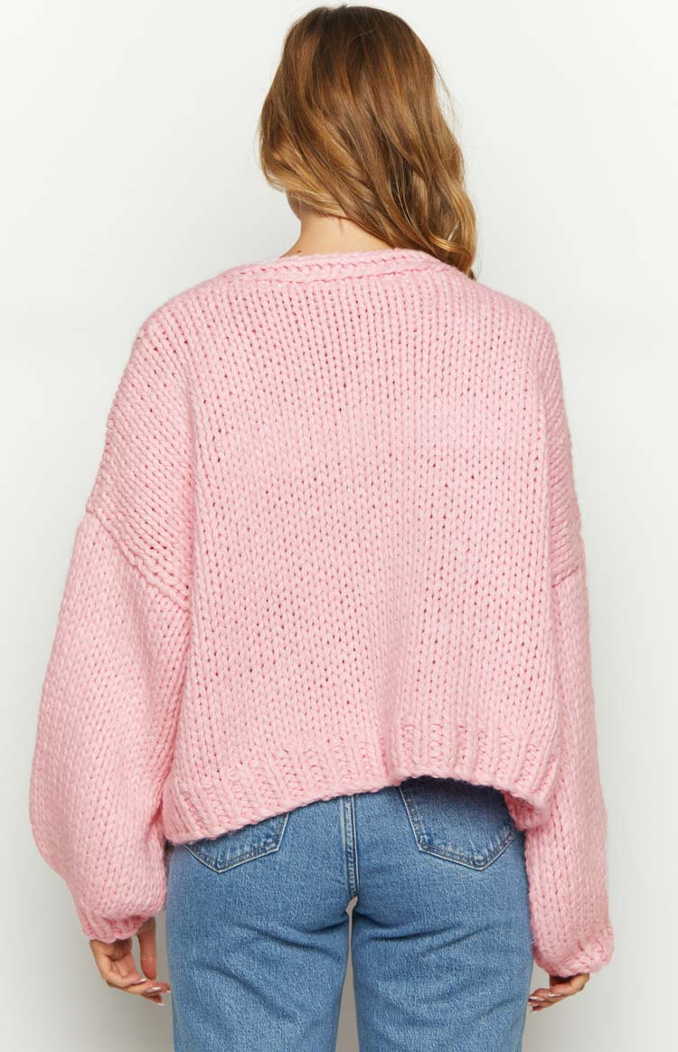 Rear view of a sorbet pink chunky knit cardigan with dropped shoulders and a ribbed hem