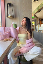 Sorbet pink chunky knit cardigan with oversized long sleeves draped over shoulders