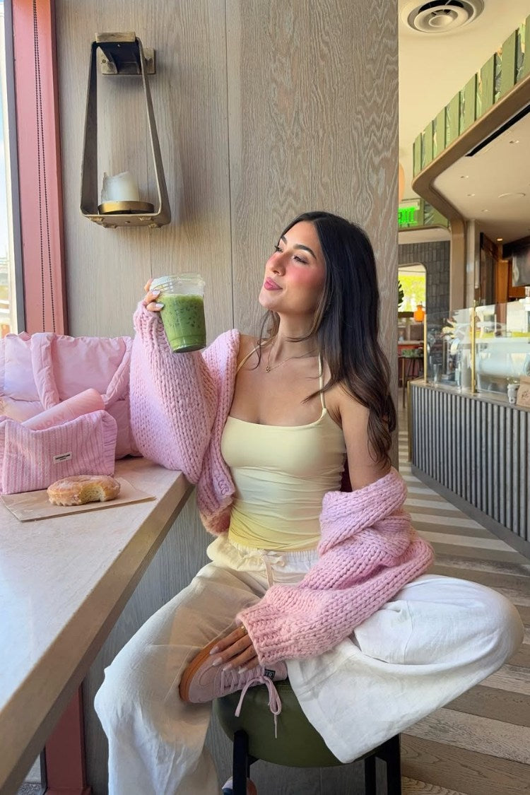 Sorbet pink chunky knit cardigan with oversized long sleeves draped over shoulders