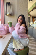Sorbet pink chunky knit cardigan worn off-shoulder, showing the relaxed fit and ribbed cuffs