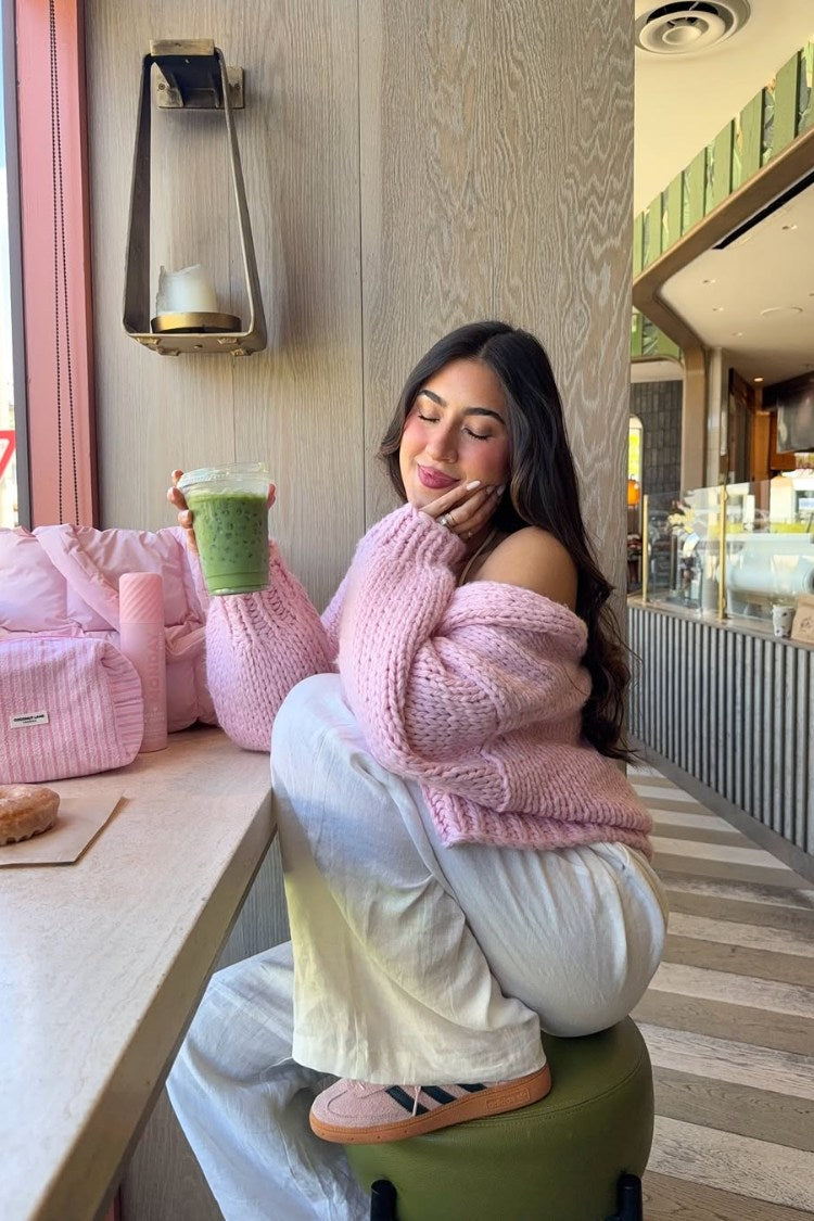 Sorbet pink chunky knit cardigan worn off-shoulder, showing the relaxed fit and ribbed cuffs