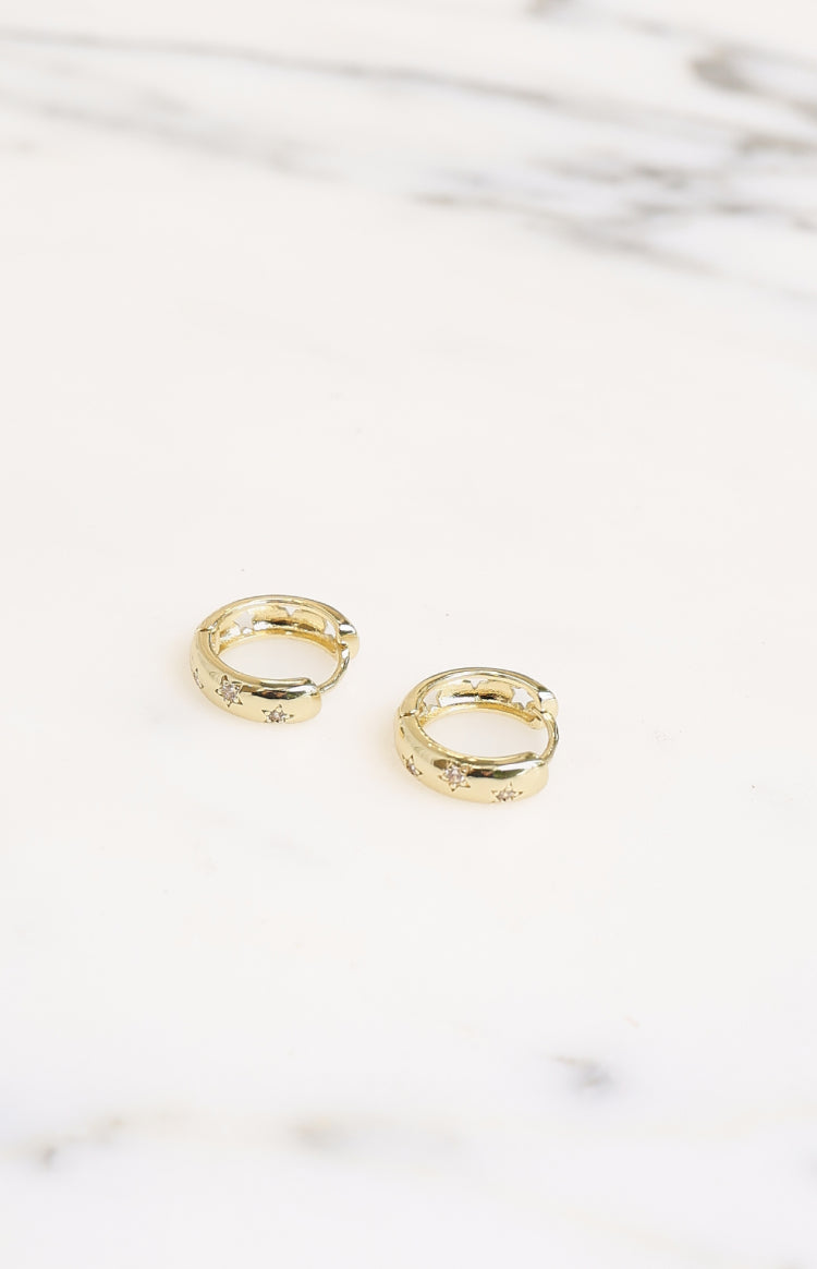 Gold hoop earrings with diamante stars and star cutouts on the inner edge, viewed from above