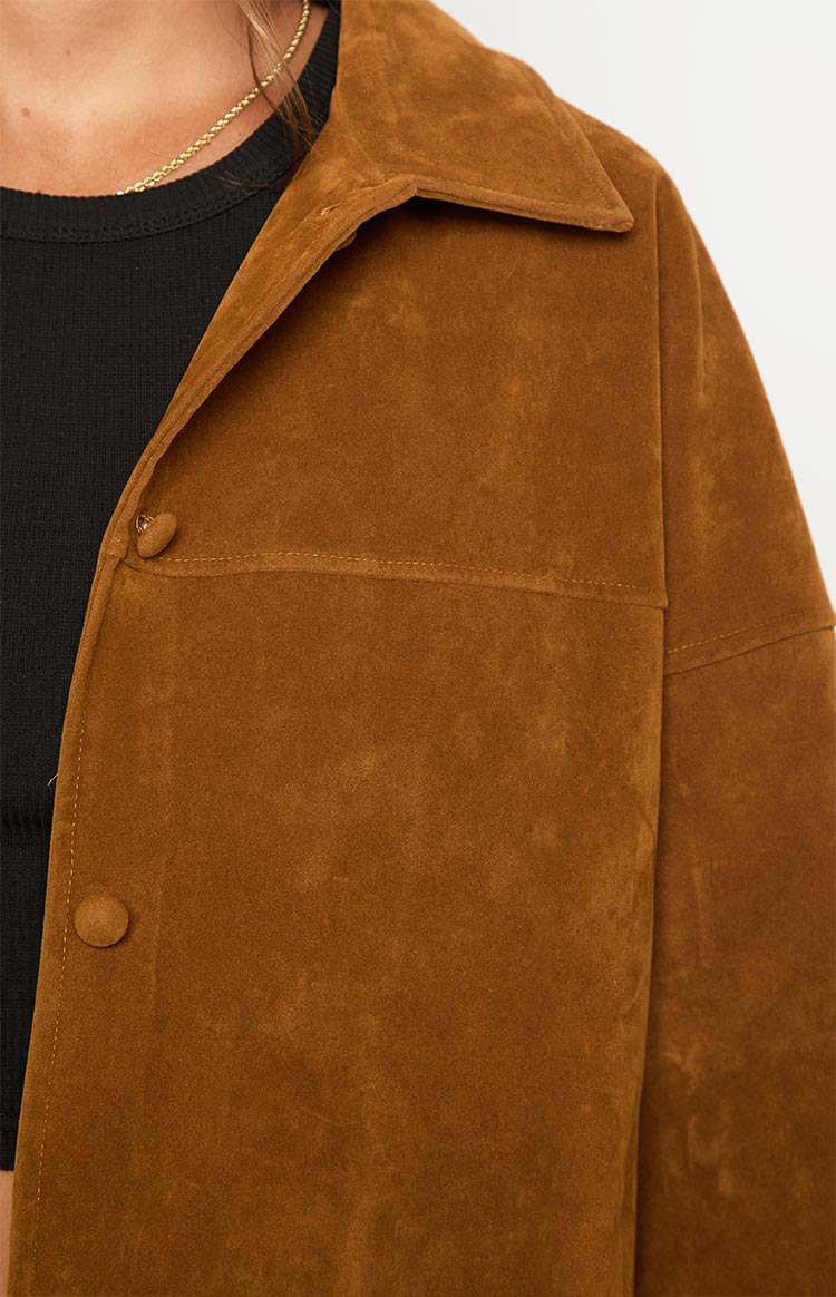 Close-up of the tan suede jacket showing the soft texture, pointed collar, and visible chest seam stitching