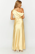 Rear view of a yellow satin one-shoulder maxi dress with draped fabric across the back and a flowy skirt