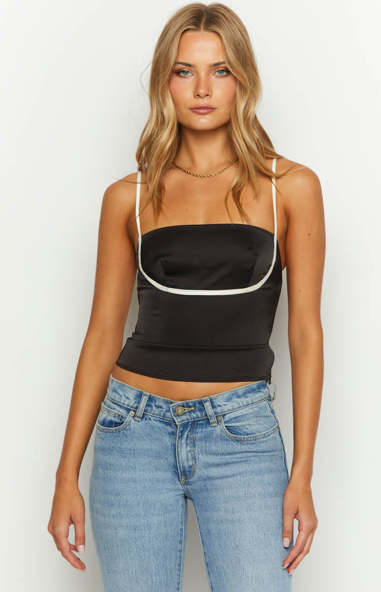 Front view of a black satin top with white piping under the bust and white spaghetti straps