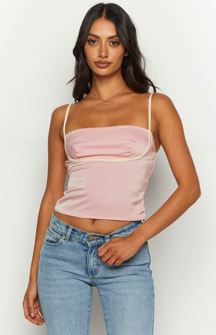 Front view of a pink satin top with a straight neckline, white piping detail, and thin spaghetti straps