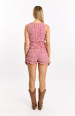 Rear view of a red and white gingham sleeveless top with a fully smocked back and ruffled hem