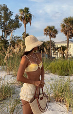 Side view of pale yellow high-waisted shorts with an all-over ruched and gathered texture