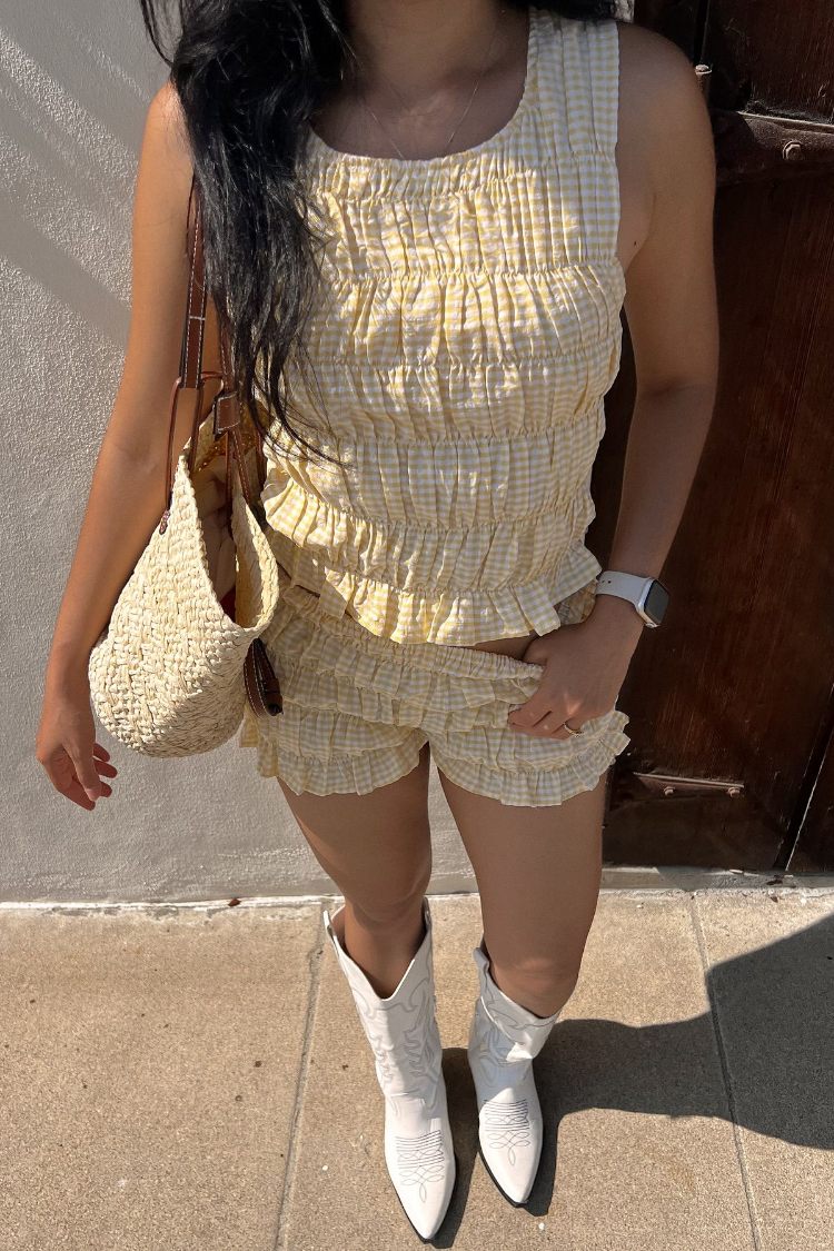 Side view of pale yellow high-waisted shorts with an all-over ruched and gathered texture