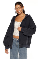 Close-up of a washed navy oversized hooded jacket with a partially open zipper and ribbed cuffs