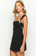 Side view of a black pinstripe mini dress with square neckline, pink ribbon ties, pleated bust, lace trim, and side cutouts