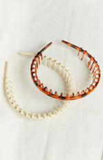 Overlapping cream and tortoiseshell headbands, both featuring a comb design with small teeth along the inner edge