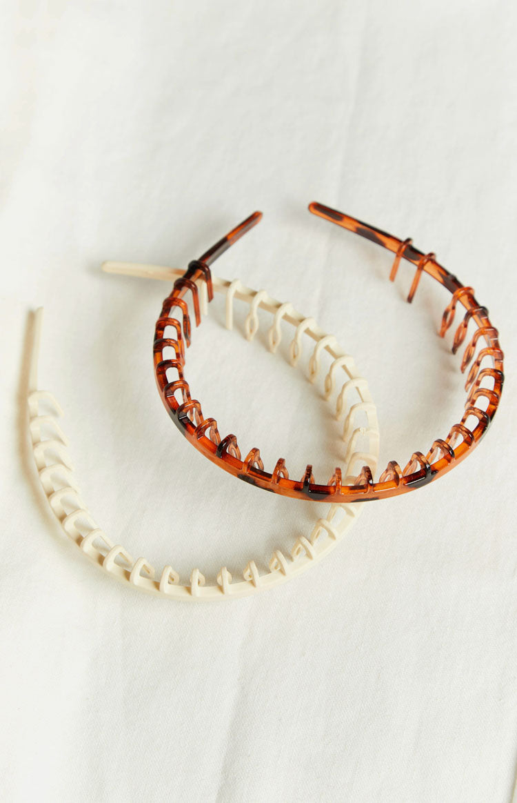 Overlapping cream and tortoiseshell headbands, both featuring a comb design with small teeth along the inner edge