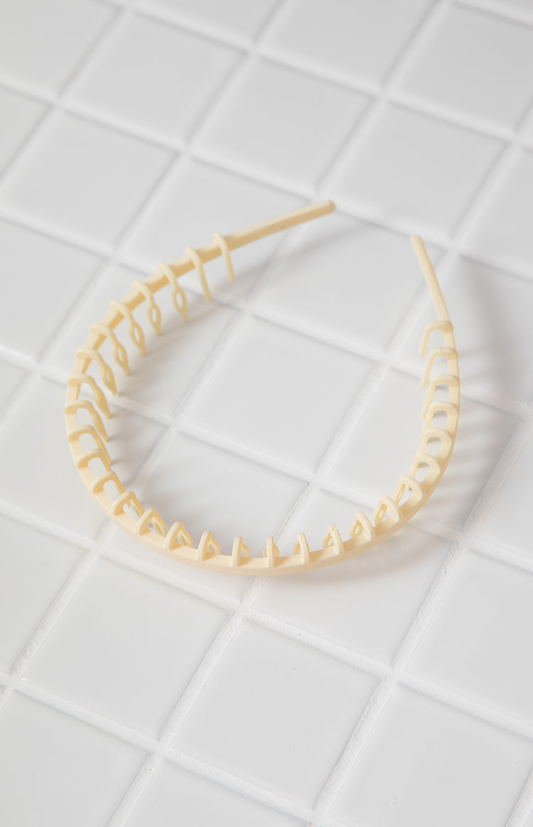 Cream plastic headband showing the full comb-like teeth structure on the inner edge