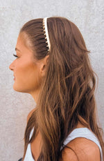 Side view of a cream headband with an inner band of comb teeth