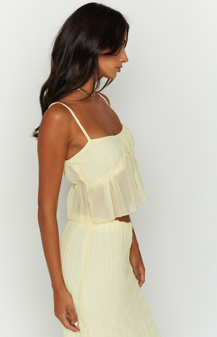 Side view of a yellow crinkled cami top with a square neckline, thin straps, and a ruffled overlay