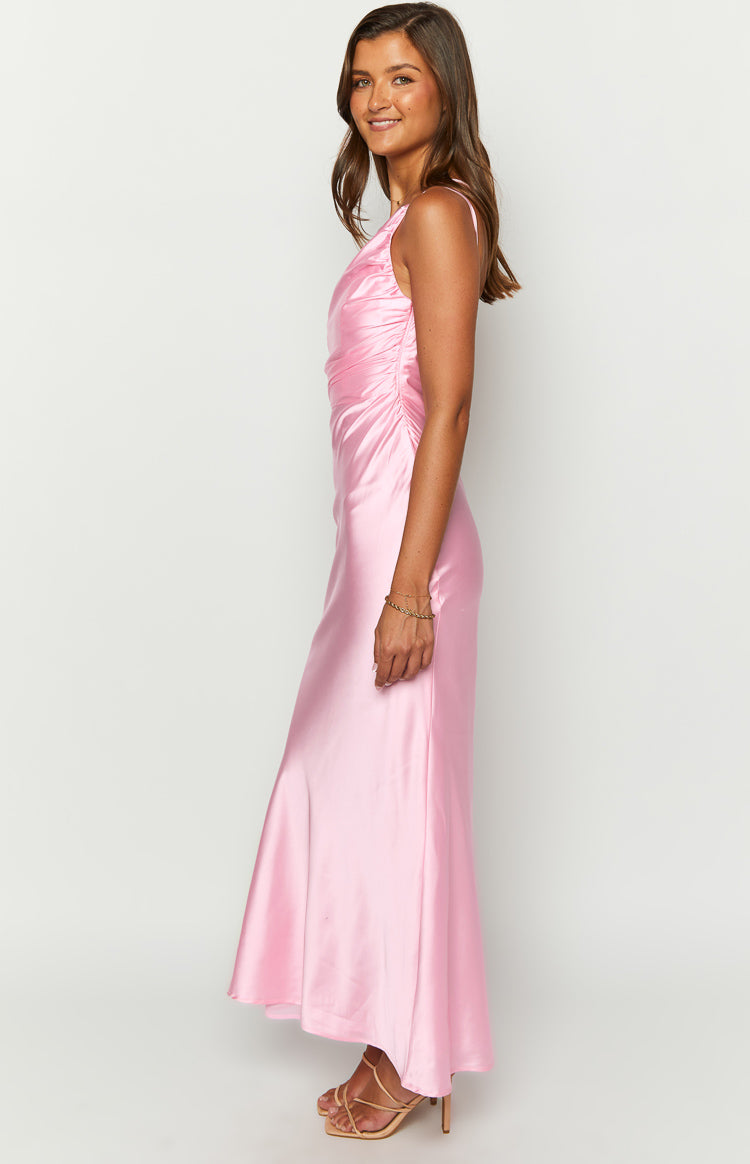 Side view of a pink satin maxi dress with ruched detailing on the side and a flowy skirt
