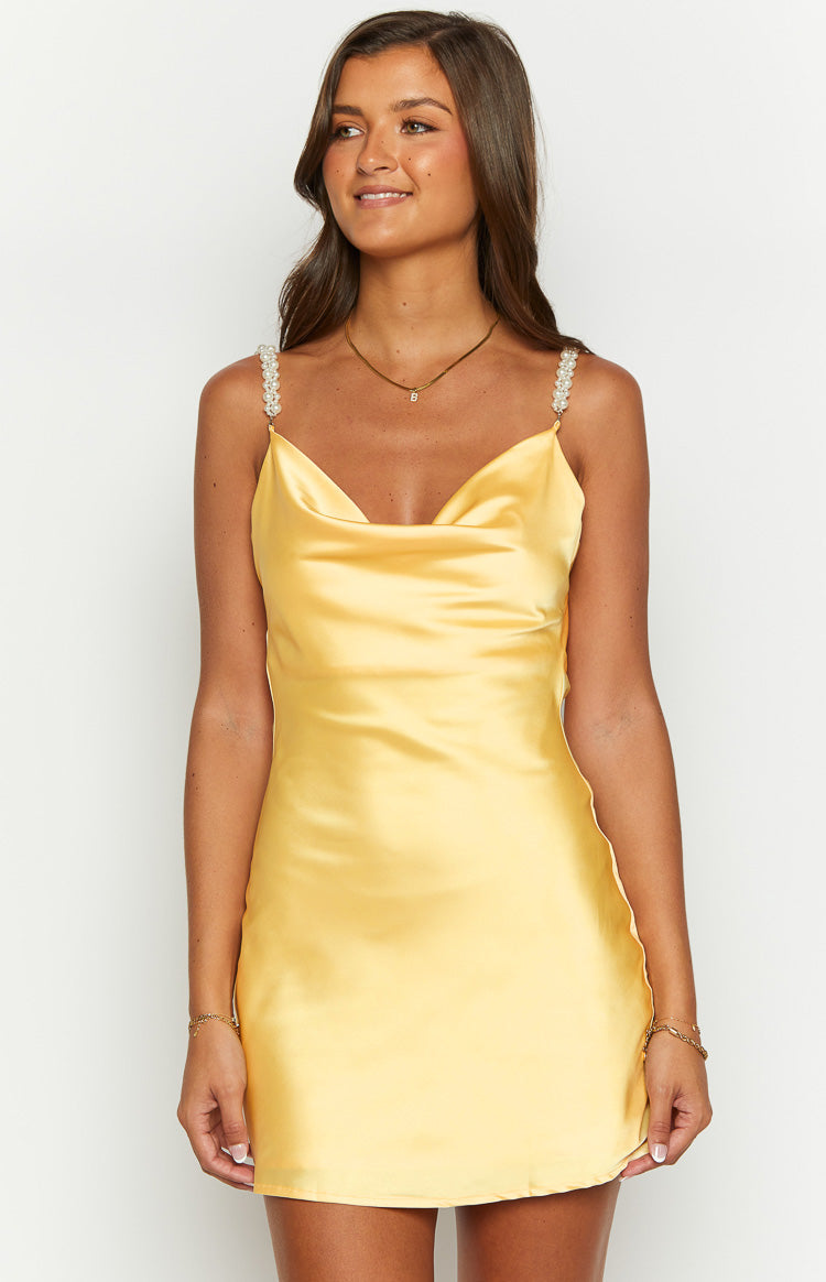 Close-up of the yellow satin mini dress showing the cowl neckline and pearl embellished spaghetti straps