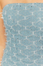 Close-up of the light blue denim fabric of the mini dress, featuring white lace bow appliques and small distressed cutouts