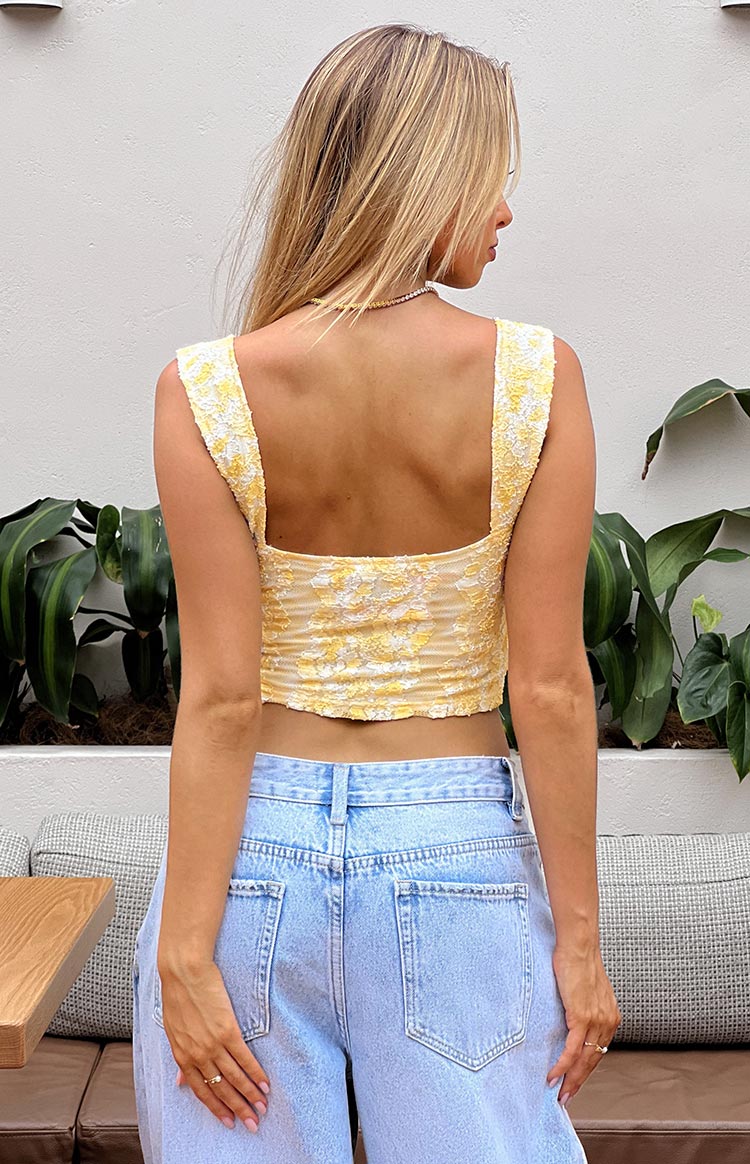 Rear view of a yellow and white lace crop top with a square back neckline