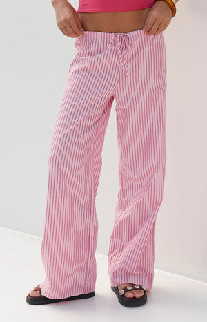 Full-length image of our model wearing a pair of pink and white striped pants with a drawstring waistband and a wide-leg fit.