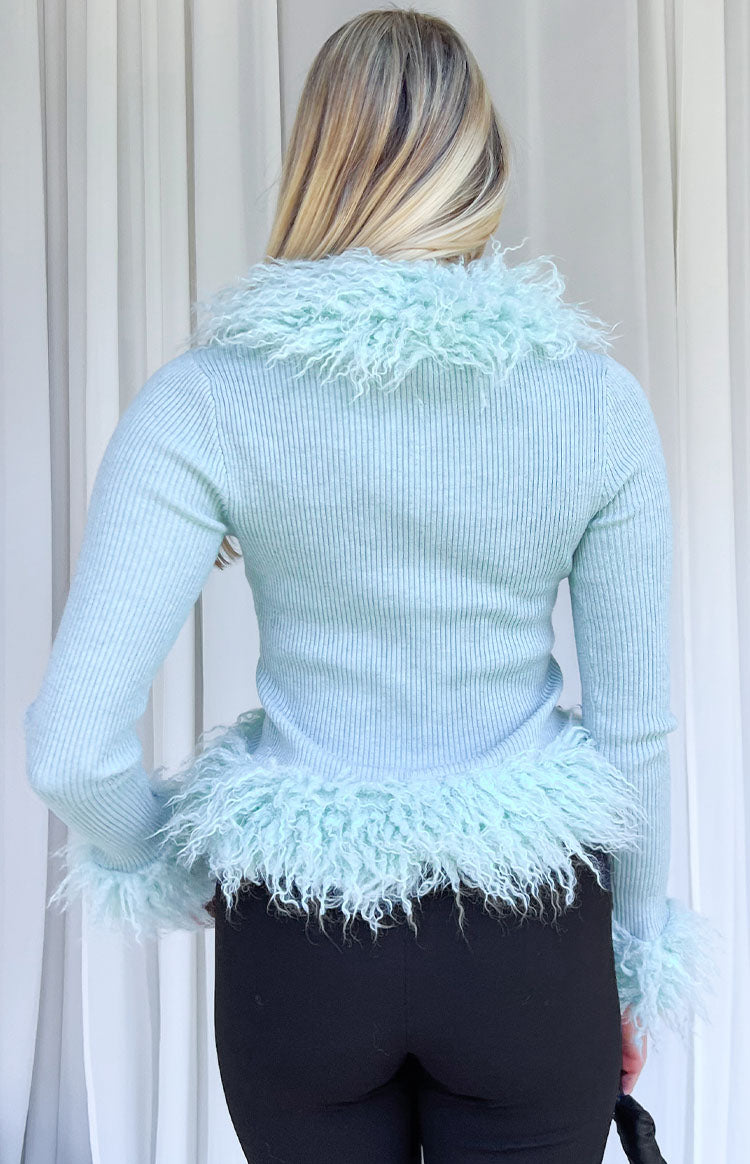 Rear view of a mint green ribbed knit cardigan with shaggy fur trim on the collar, hem, and cuffs