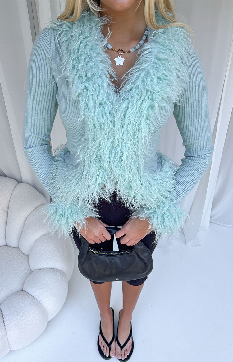 Full view of a mint green ribbed knit cardigan with shaggy fur trim around the V-neckline and cuffs