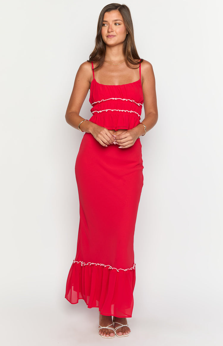 Full length front view of a red maxi skirt with a fitted silhouette and ruffled hem with white trim