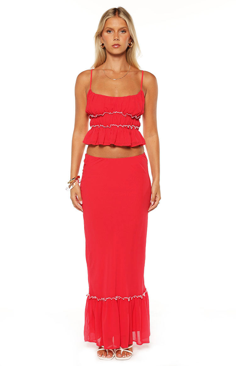 Red maxi skirt with a fitted waist and a flowy silhouette, featuring a ruffled hem with white stitching